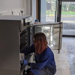 Engineering student crouching in front of a testing machine, undertaking carbonation tests